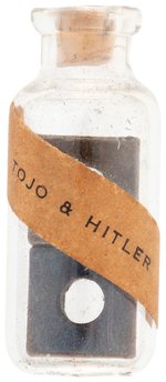 "TOJO & HITLER" PAPER LABEL ON GLASS VIAL W/CORK STOPPER HOLDING TWO SQUARE METAL NUTS.